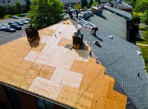 workers stapling shingles to roof
